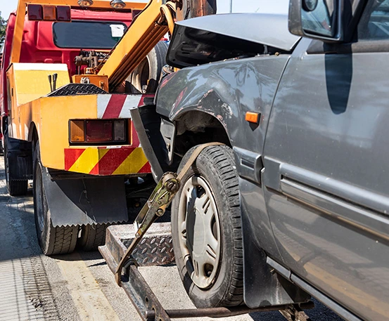 A tow truck loading a damaged car onto its flatbed