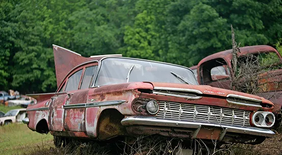 A heavily rusted, abandoned 1959 Chevrolet Impala in a field