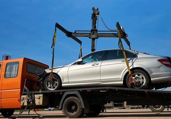 A white Mercedes-Benz C-Class car being towed on a flatbed truck